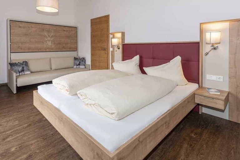 Modernes Doppelzimmer mit Holzboden, Sofa und gemütlicher Atmosphäre in der Pension Niederreiter