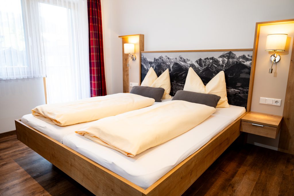 Cozy Room with Double Bed, Wooden Furniture, and Balcony View of the Mountains in Maria Alm