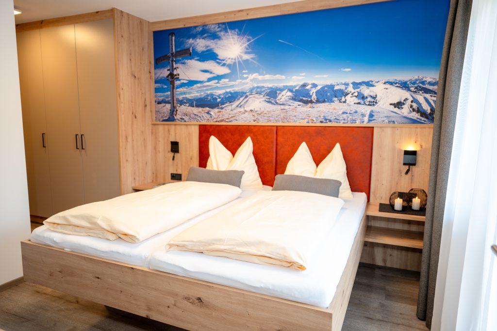 Cozy Room with Double Bed, Wooden Furniture, and Balcony View of the Mountains in Maria Alm